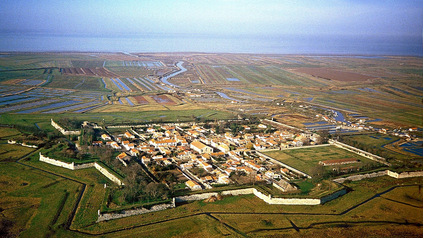 Vue aérienne de la citadelle de Brouage, remparts en étoile au milieu des marais, la mer à l'horizon