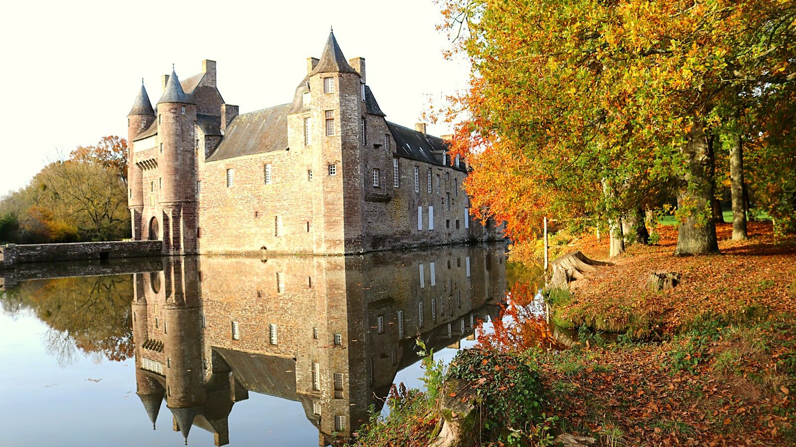 Le château de Trécesson et ses murs de schiste reflétés dans l'étang, dans le Morbihan