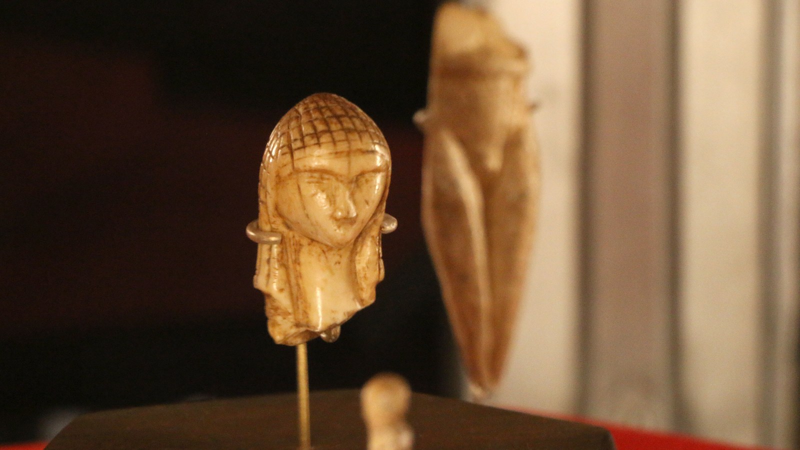 La Dame de Brassempouy, petite tête en ivoire au visage triangulaire et à la coiffure quadrillée, exposée sur une tige au musée d'Archéologie nationale
