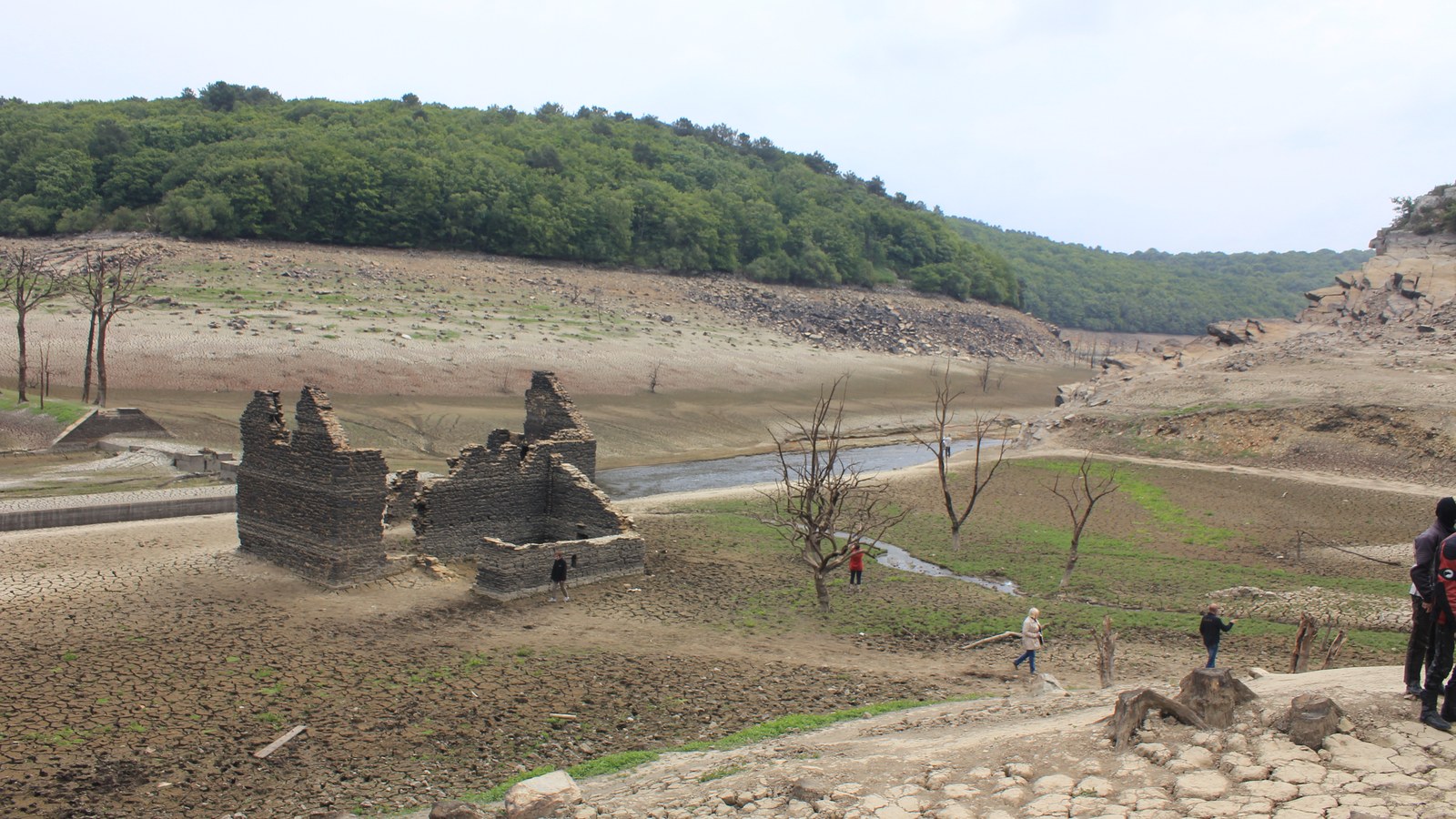 Ruines d'une maison éclusière et d'une écluse sur le fond asséché du lac de Guerlédan en juin 2015, avec des promeneurs
