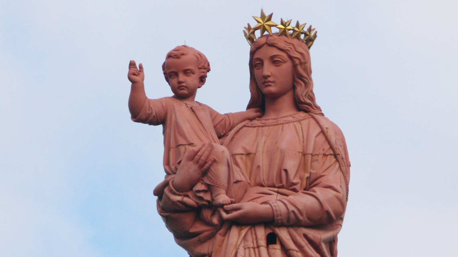 La statue rouge de Notre-Dame de France au Puy-en-Velay, Vierge couronnée d'étoiles dorées portant l'Enfant Jésus qui bénit la ville