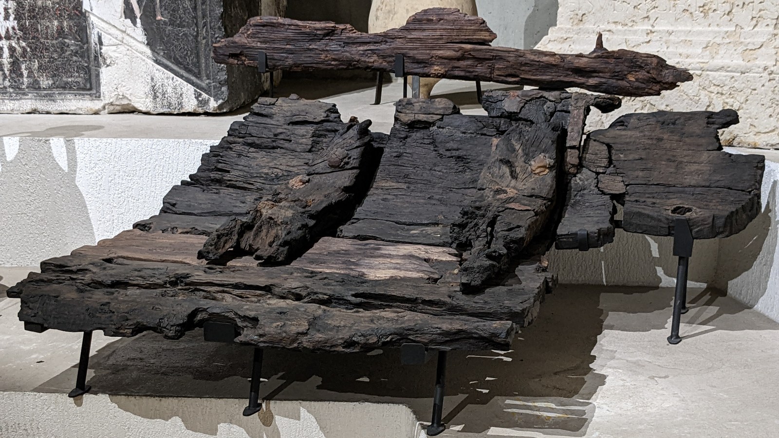 Fragment de coque en bois noirci d'un chaland gallo-romain à fond plat posé sur des supports métalliques au musée Lugdunum