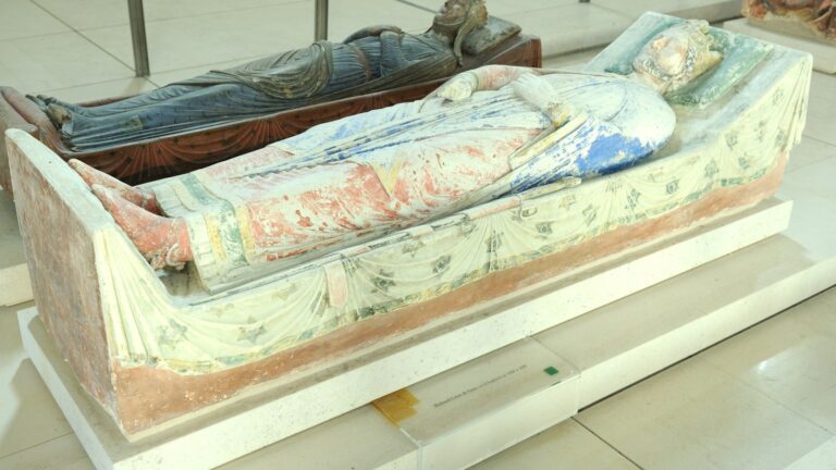 Gisant polychrome de Richard Cœur de Lion dans l'abbatiale de Fontevraud, couronné et vêtu d'un manteau peint, avec un autre gisant en bois sombre à l'arrière-plan