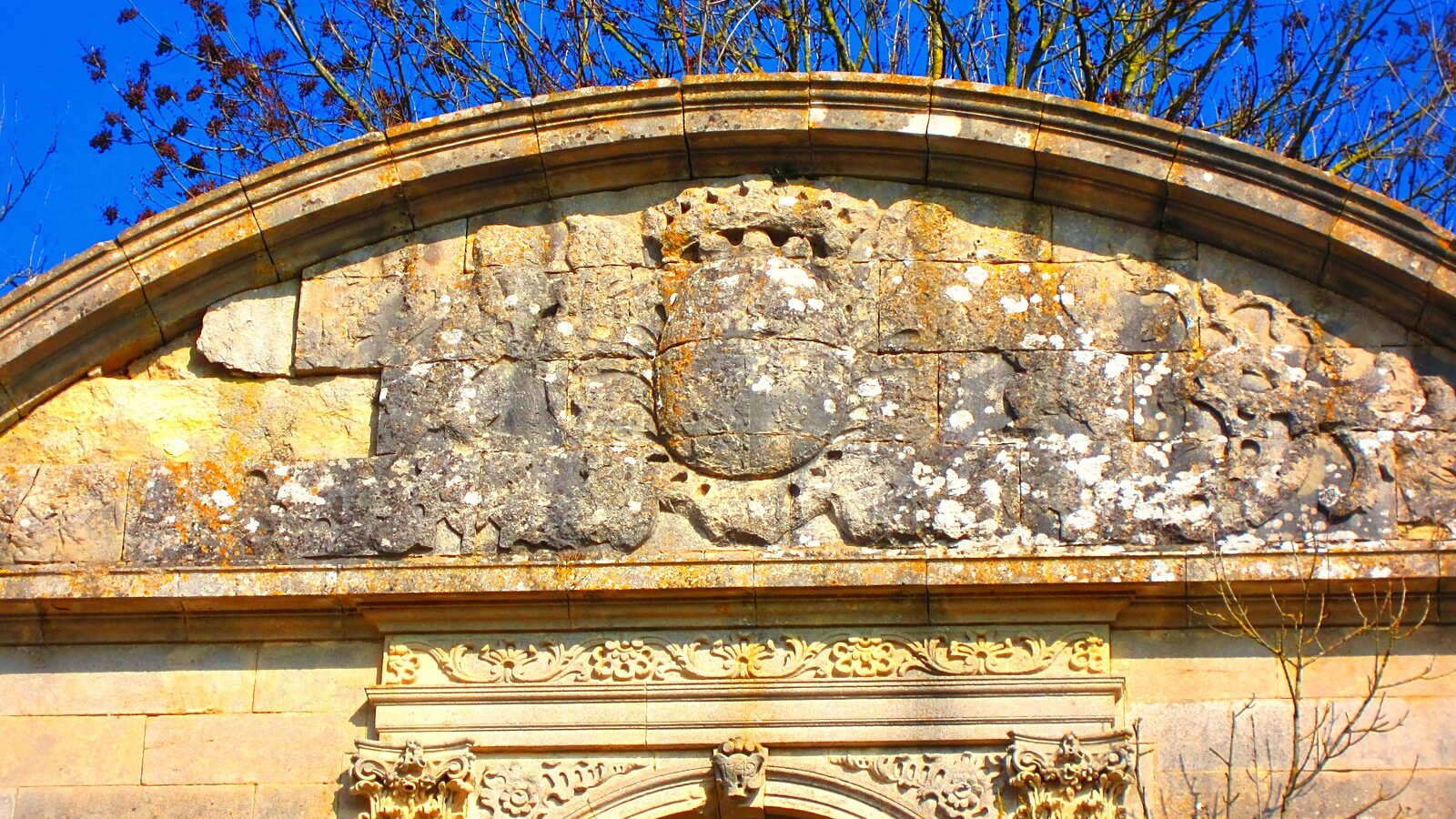 Le fronton de pierre de l'abbaye de Saint-Benoît-en-Woëvre, en ruine, et son blason martelé