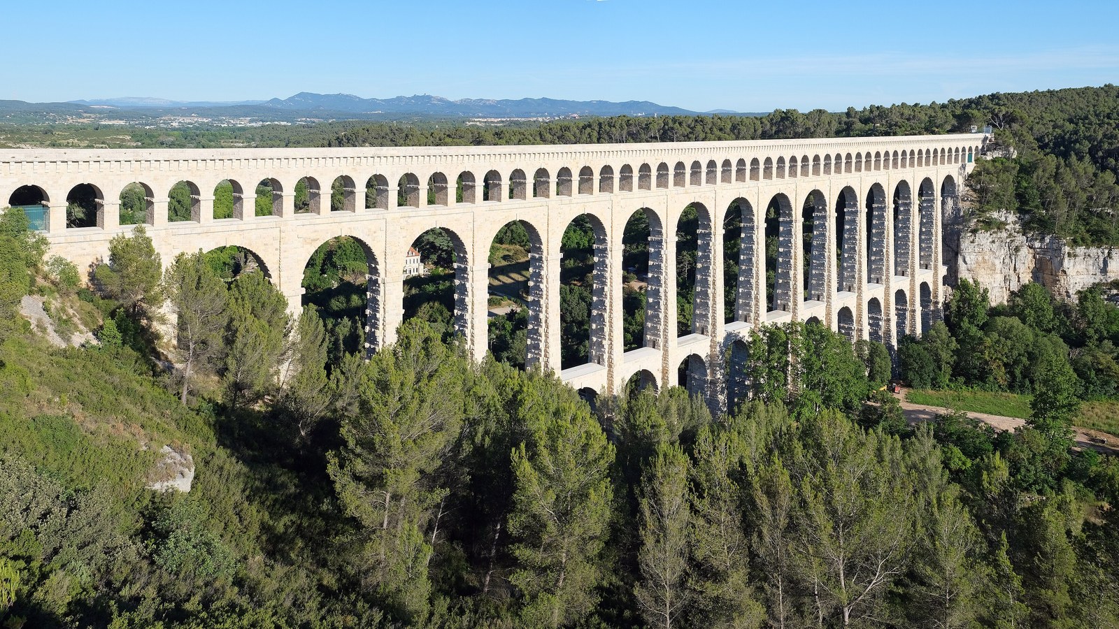 L'aqueduc de Roquefavour et ses trois étages d'arches en pierre au-dessus d'une vallée boisée, à Ventabren