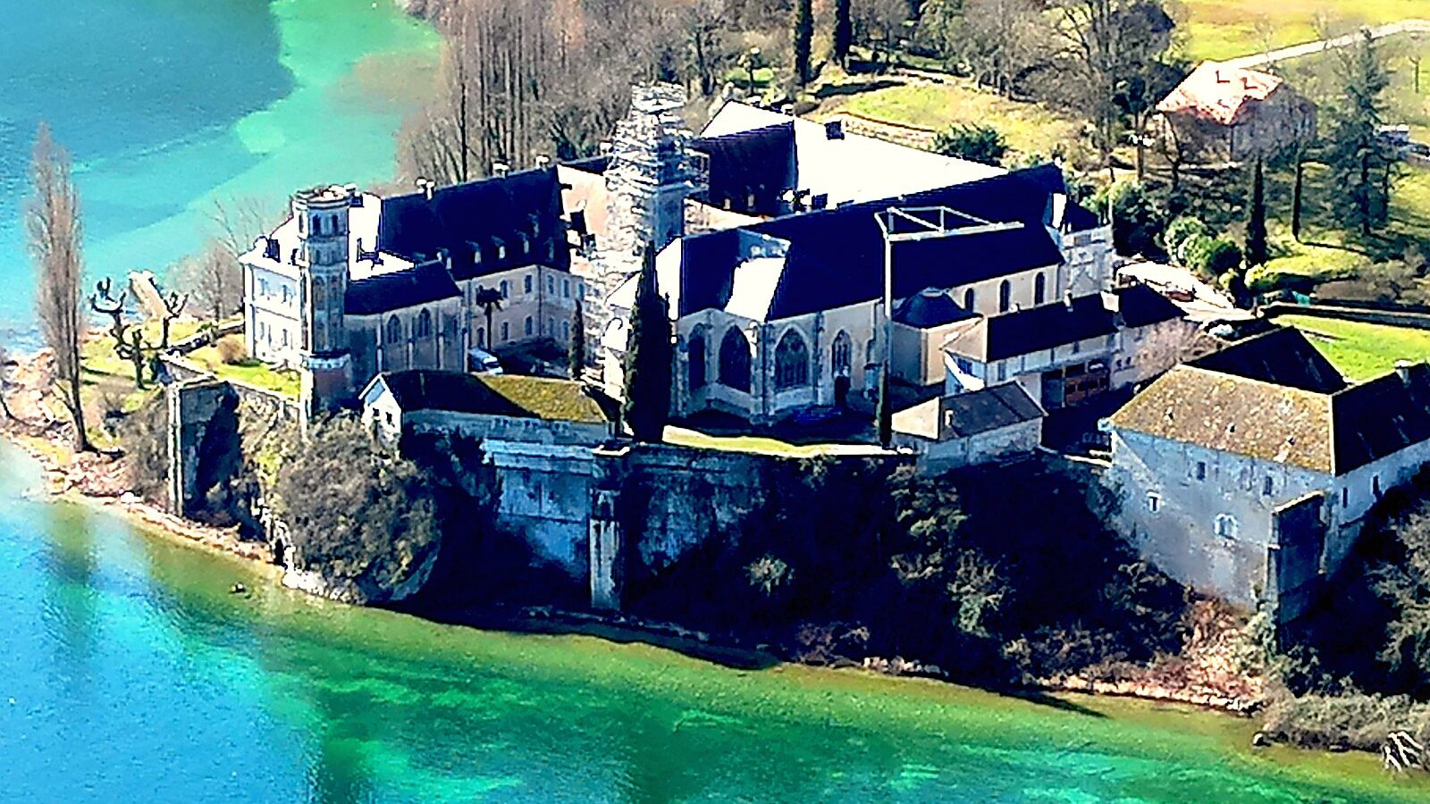 L'abbaye d'Hautecombe sur son promontoire et les eaux peu profondes de la baie, vues du ciel