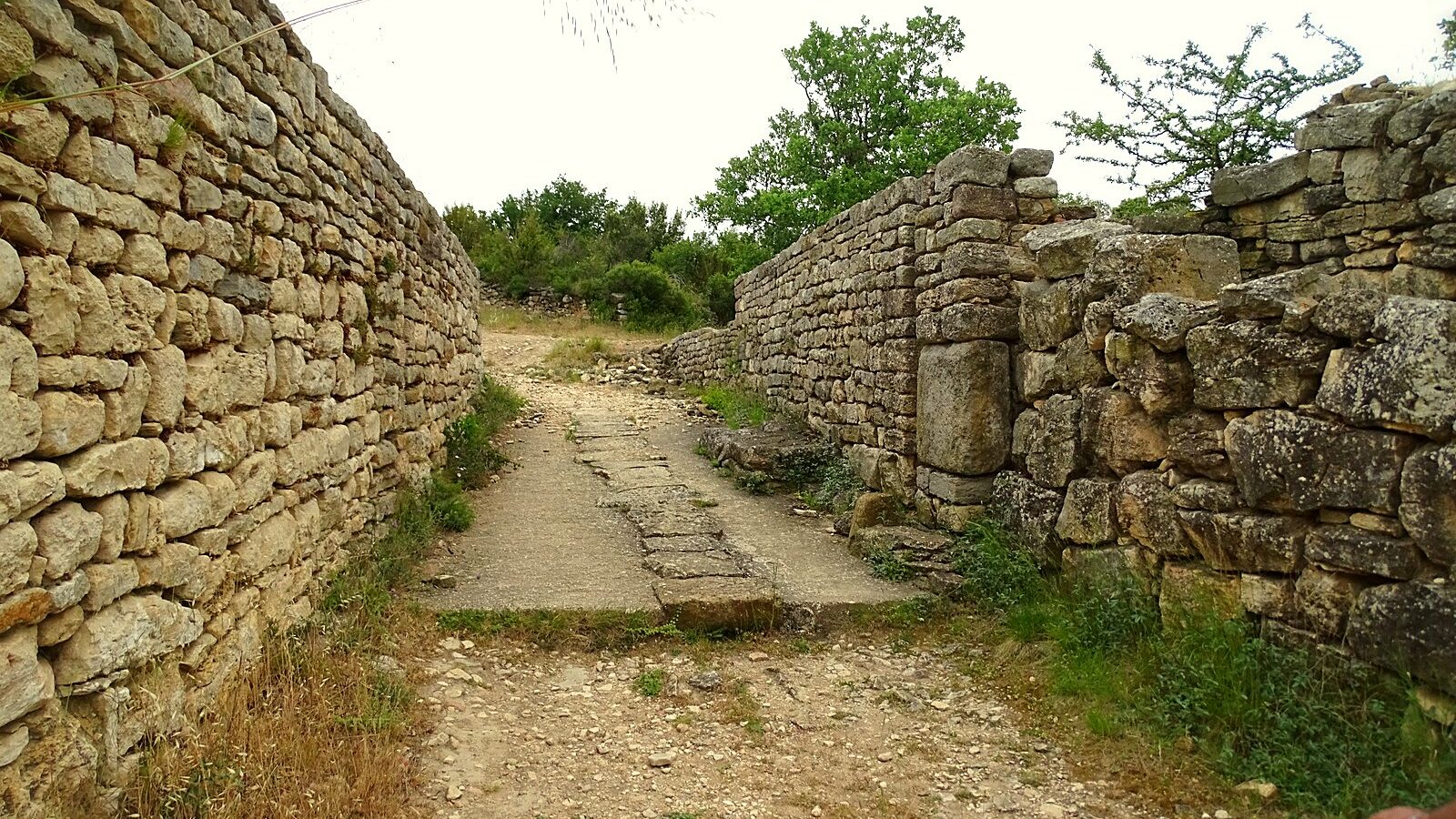 Une rue dallée du Camp de César de Laudun, entre deux murs antiques dégagés par les fouilles