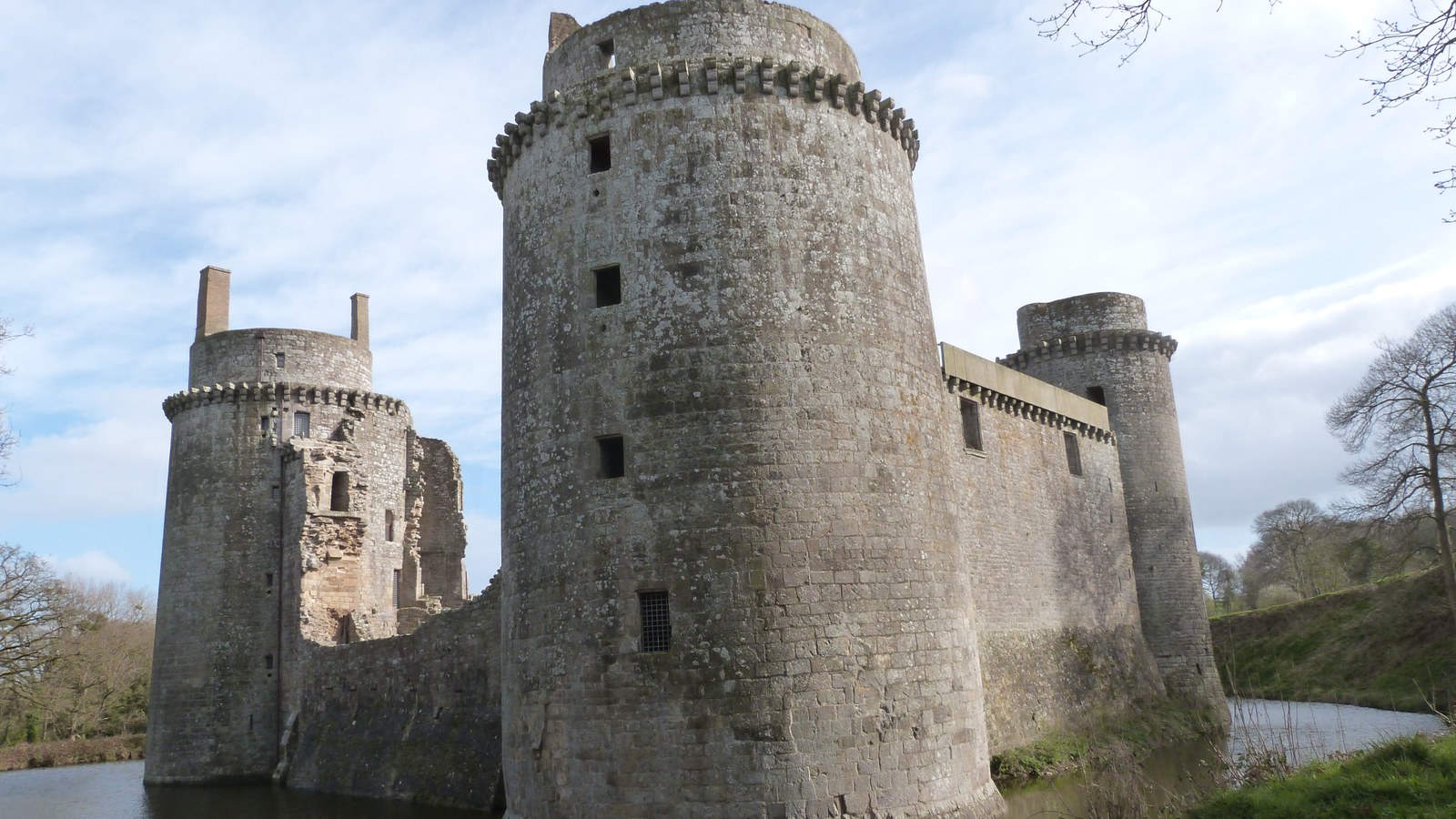 Les tours rondes du château de la Hunaudaye, en granite gris, dressées au-dessus de leurs douves sous un ciel nuageux