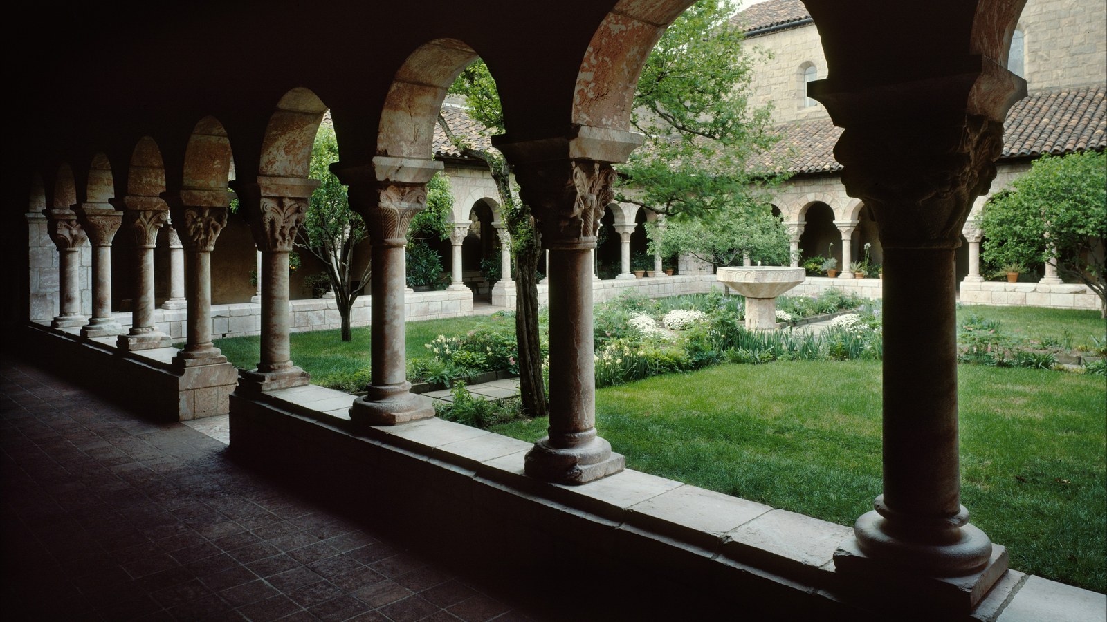 Galerie à arcades en marbre rose du cloître de Cuxa aux Cloisters de New York, ouverte sur un jardin
