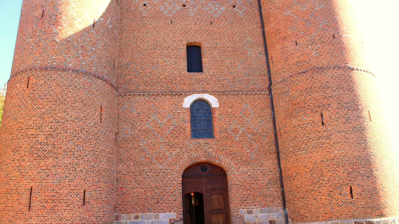 Le donjon de brique de l'église de Plomion, ses deux tours rondes et ses meurtrières
