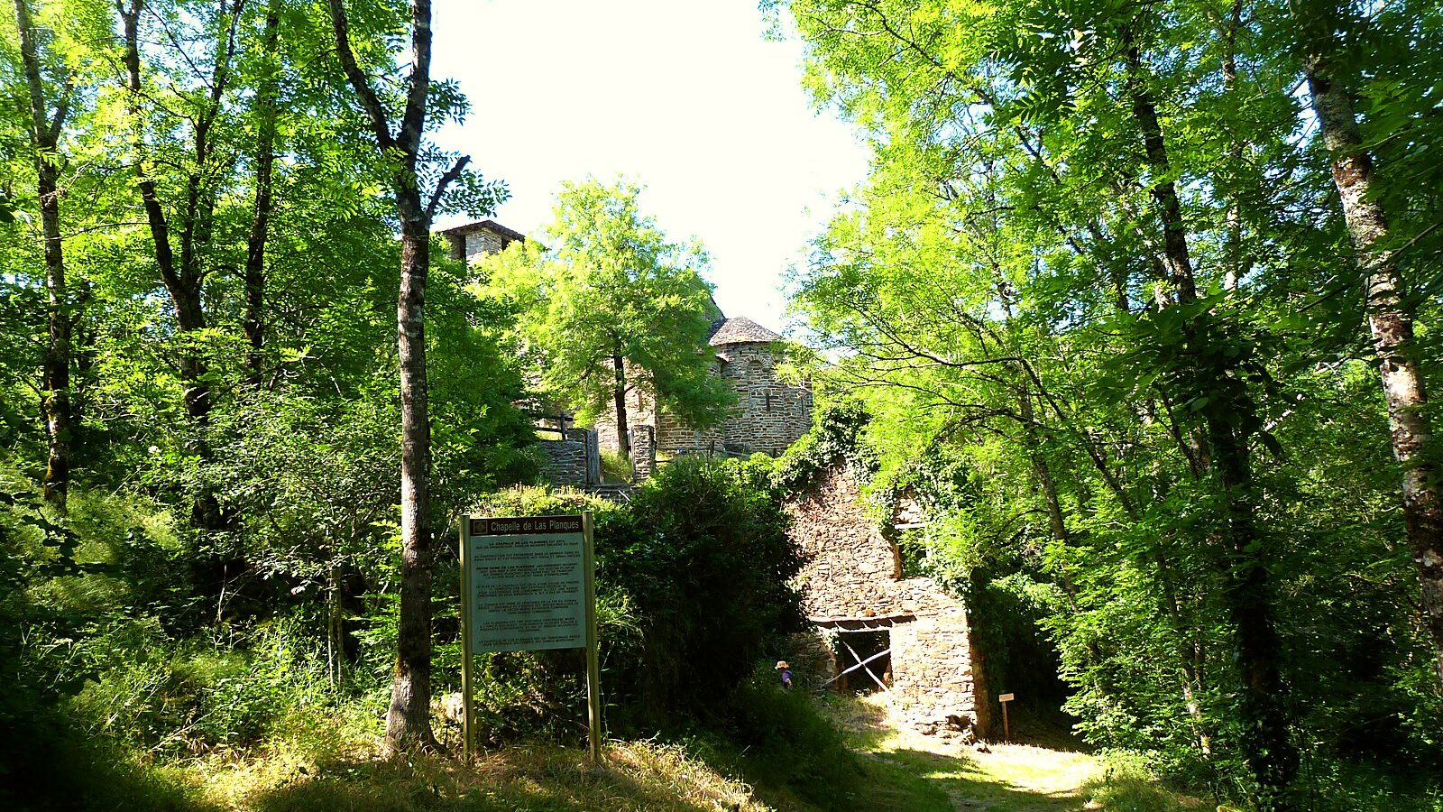 Le sentier qui mène à l'église de Las Planques, son abside et son clocher dans les arbres