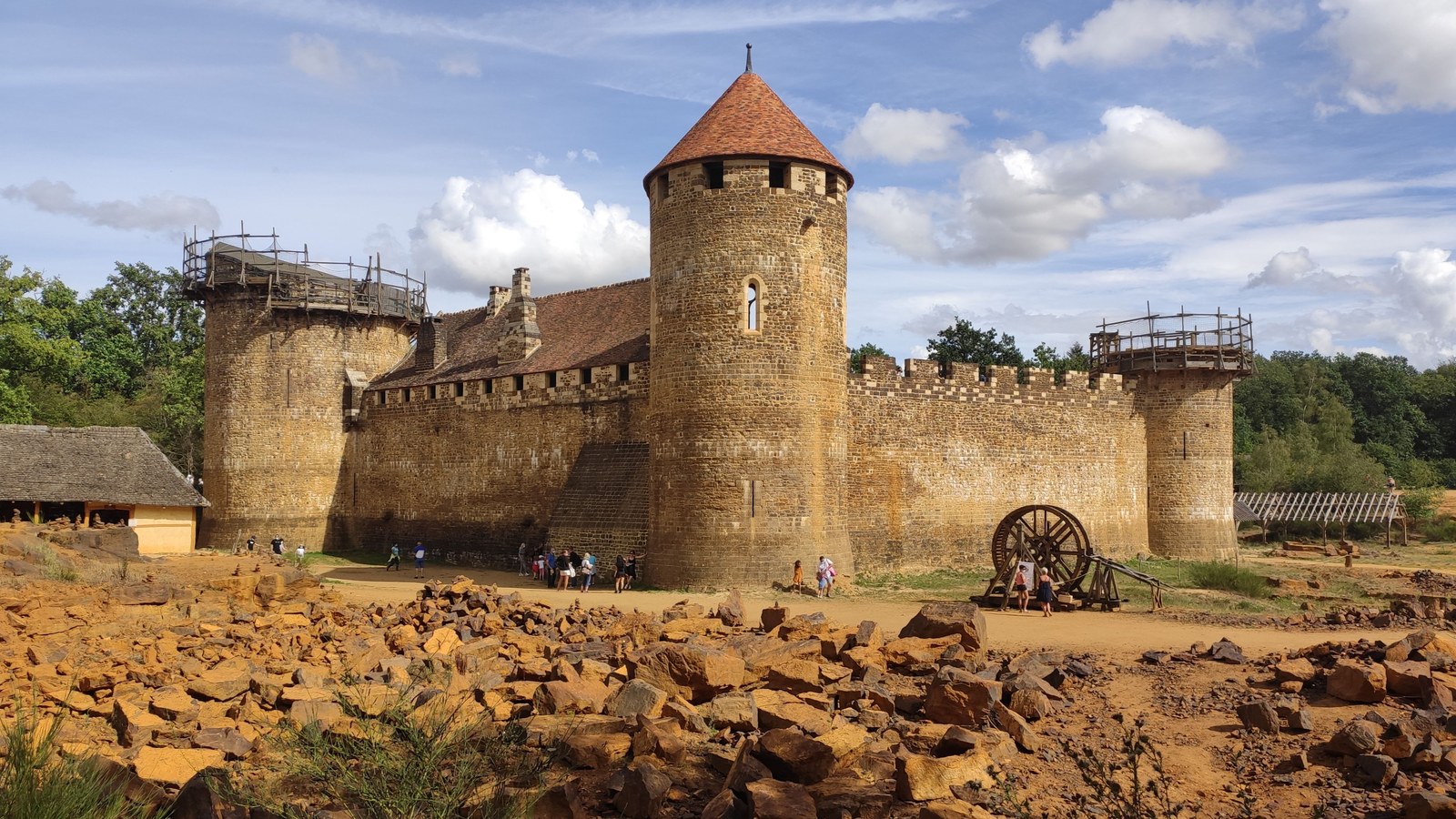 Le château de Guédelon en construction, ses tours en grès ocre et des blocs de pierre au premier plan