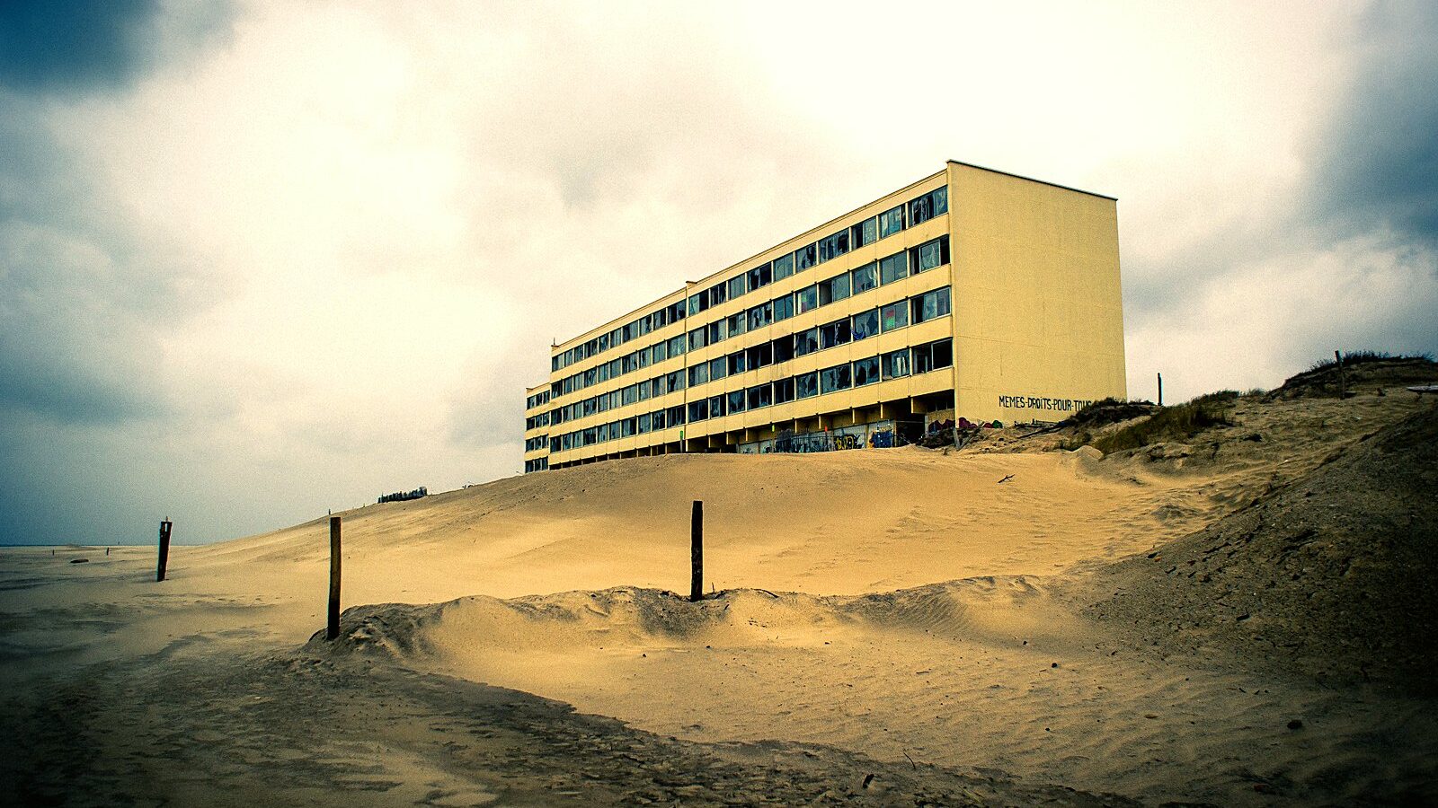 L'immeuble Le Signal, vide, au sommet de la dune de sable, vu depuis la plage