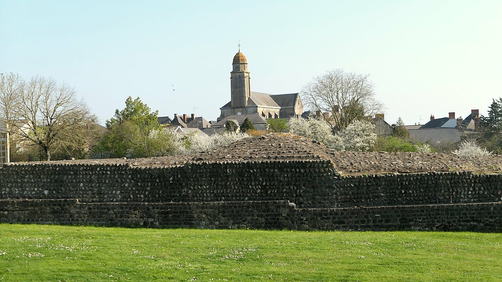Le mur de la forteresse romaine de Jublains, avec le clocher de l'église du village derrière