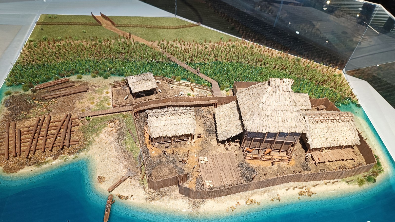 Maquette du site médiéval de Colletière exposée au musée archéologique du lac de Paladru, avec ses maisons à toit de chaume et sa palissade au bord de l'eau