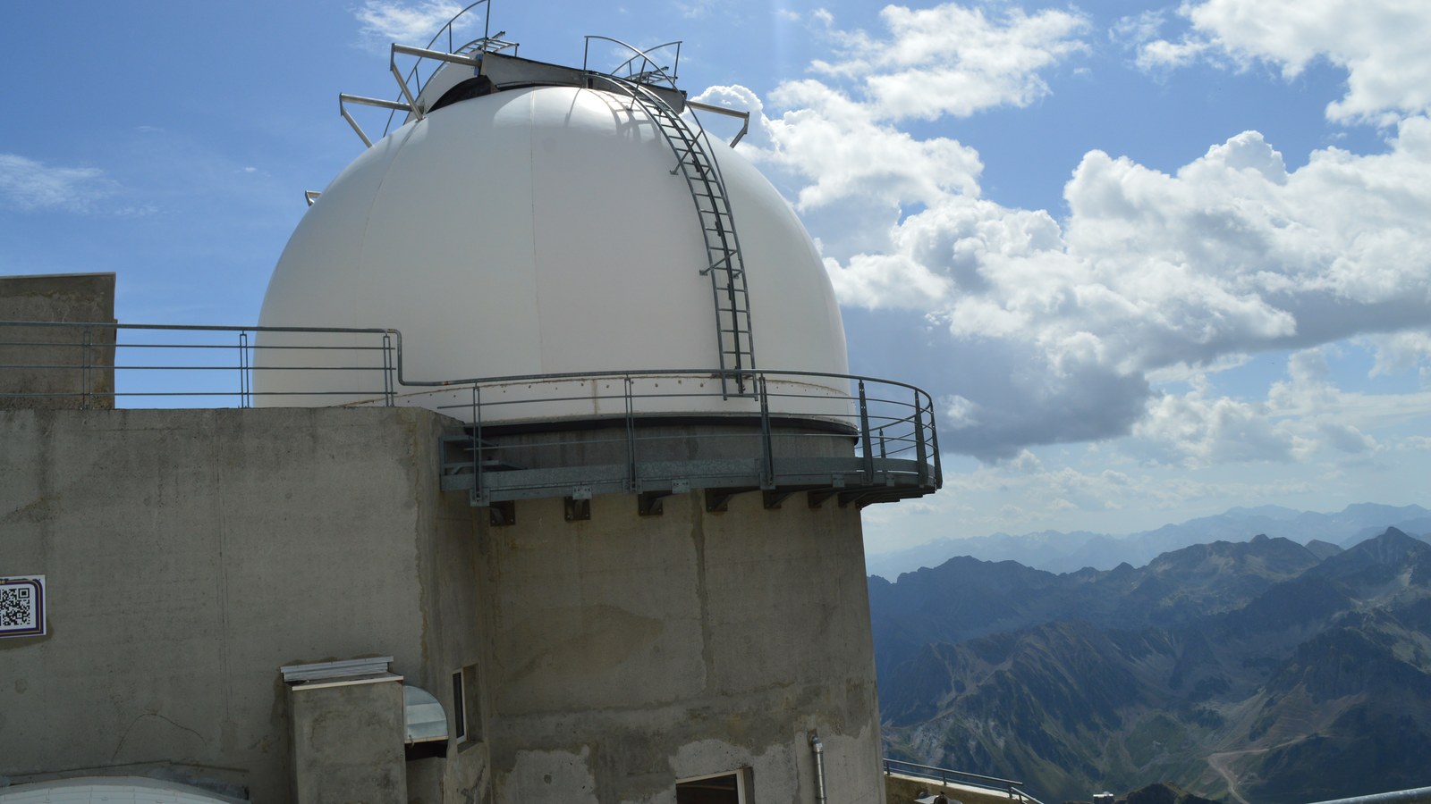 Coupole blanche d'un télescope de l'observatoire du pic du Midi, avec les sommets des Pyrénées en arrière-plan