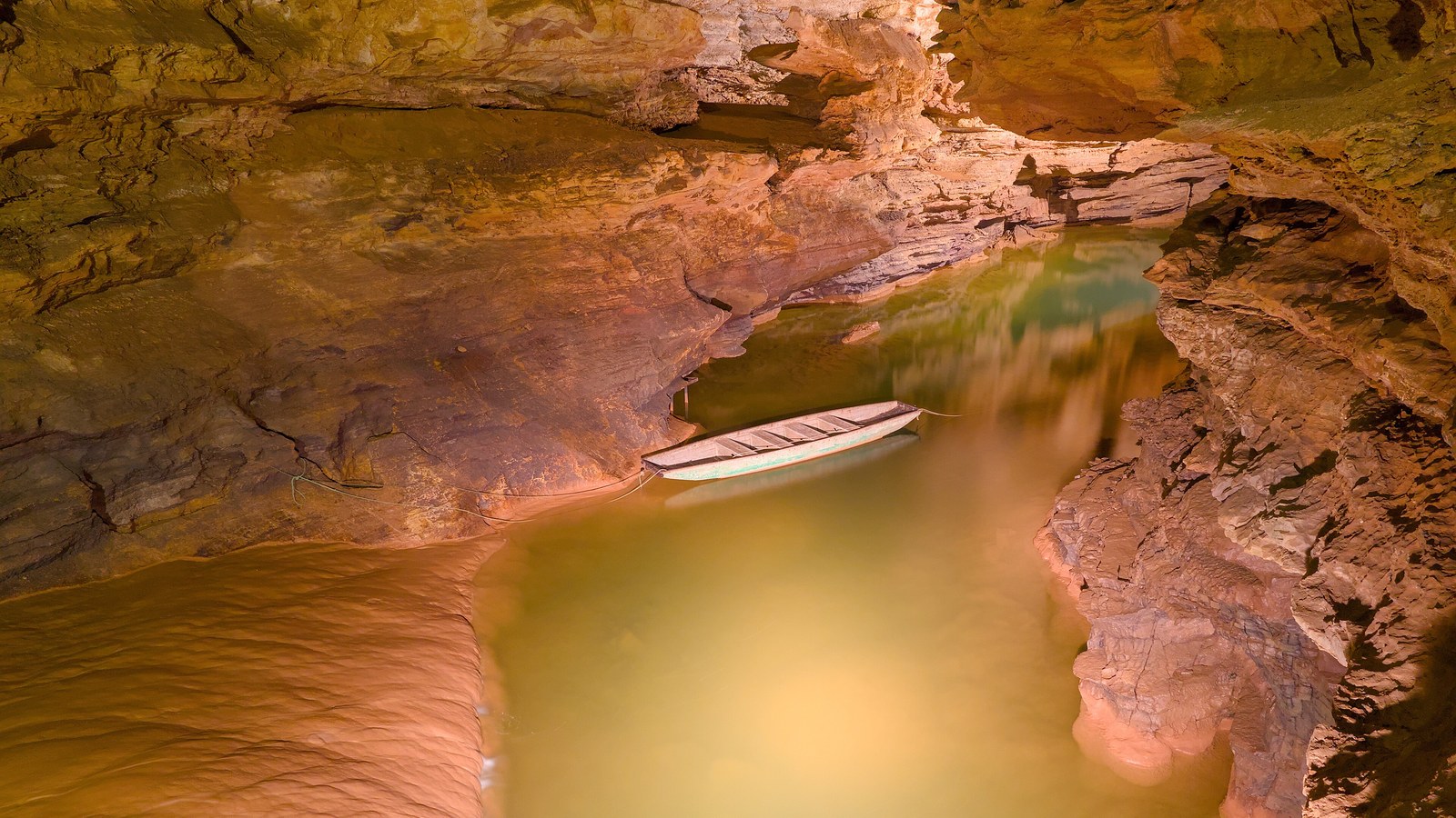 Rivière souterraine aux eaux vertes dans une galerie calcaire du gouffre de Padirac, avec une barque amarrée