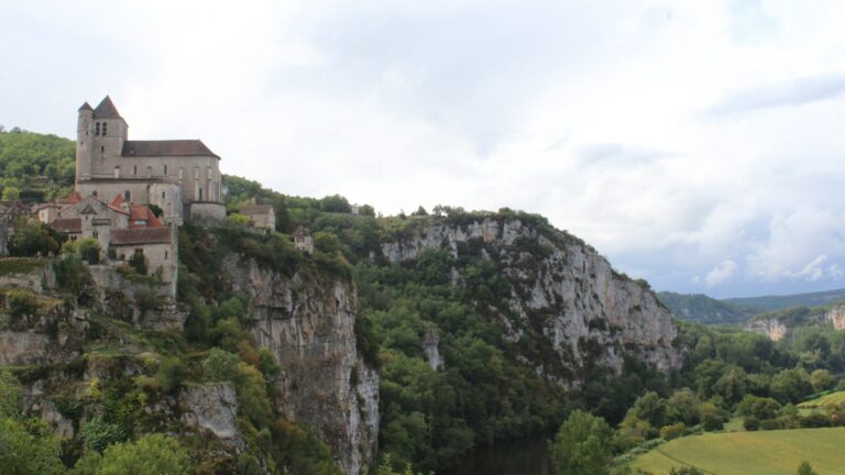 Le village de Saint-Cirq-Lapopie et son église au bord d'une falaise calcaire dominant la vallée boisée du Lot