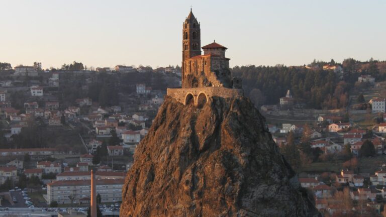 La chapelle Saint-Michel et son clocher au sommet du rocher d'Aiguilhe, éclairés par le soleil couchant