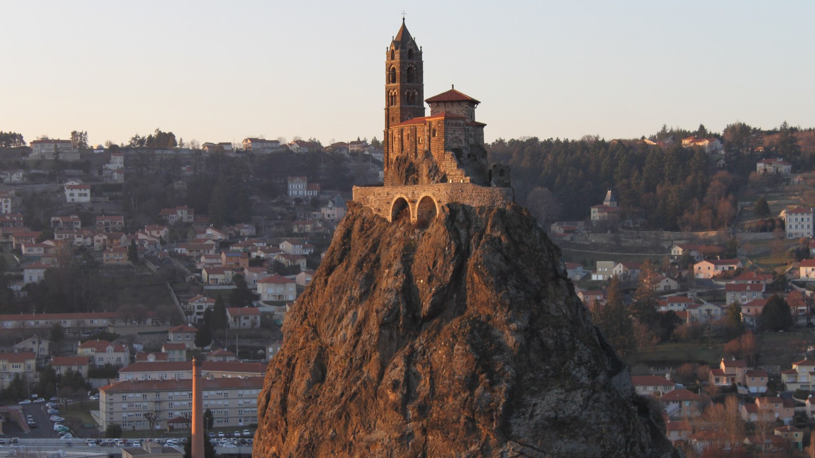 La chapelle Saint-Michel et son clocher au sommet du rocher d'Aiguilhe, éclairés par le soleil couchant